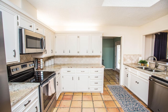 kitchen with white cabinetry, stainless steel appliances, sink, and light stone counters