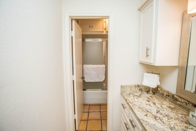 bathroom featuring tile patterned flooring, vanity, and enclosed tub / shower combo