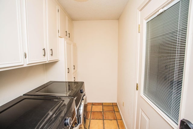 laundry area with cabinets, tile patterned floors, washing machine and clothes dryer, and a textured ceiling