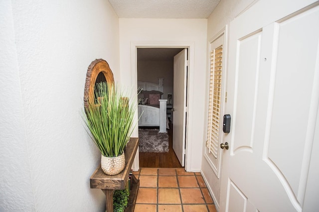 corridor with light tile patterned floors and a textured ceiling