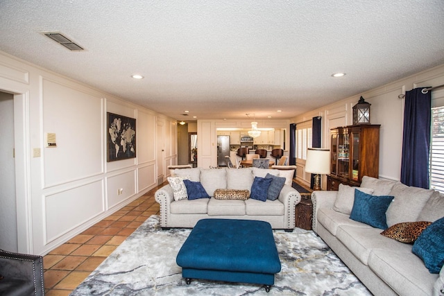 living room with light tile patterned flooring, ornamental molding, and a textured ceiling