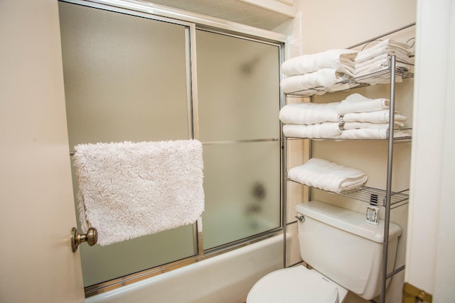 bathroom with toilet and bath / shower combo with glass door