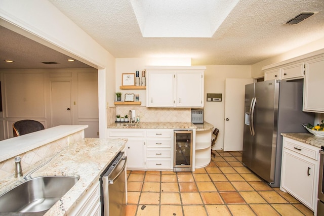 kitchen with white cabinetry, appliances with stainless steel finishes, sink, and wine cooler