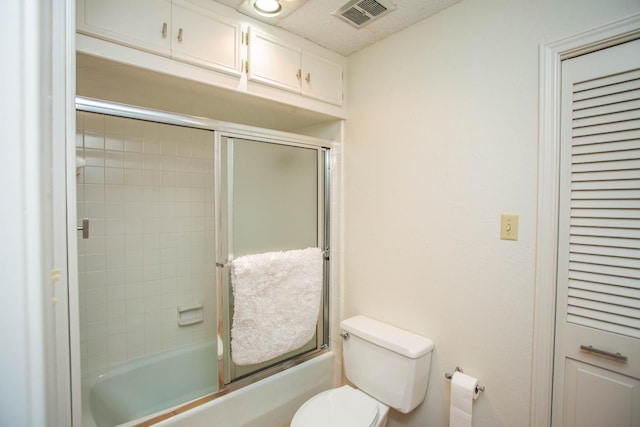 bathroom featuring enclosed tub / shower combo and toilet