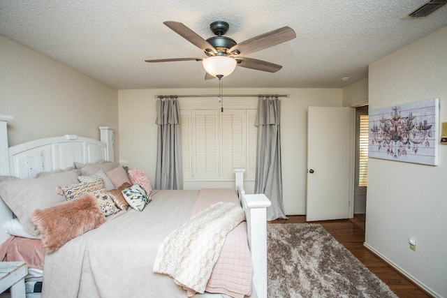 bedroom with dark hardwood / wood-style flooring, ceiling fan, and a textured ceiling