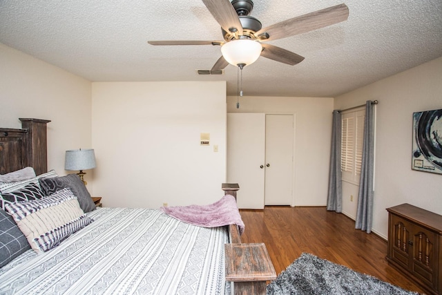 bedroom with ceiling fan, dark hardwood / wood-style floors, and a textured ceiling