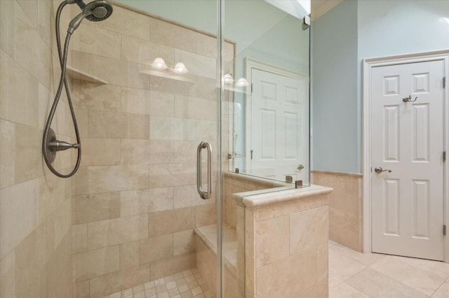 bathroom featuring wainscoting, tile walls, and a shower stall