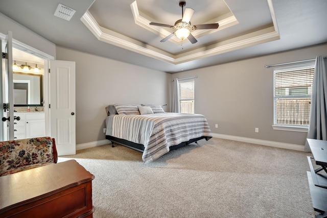 carpeted bedroom featuring ceiling fan, ensuite bathroom, and a tray ceiling