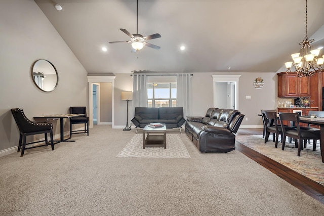 living room with ceiling fan with notable chandelier and high vaulted ceiling