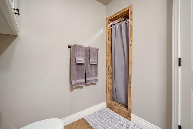 bathroom with toilet, curtained shower, and tile patterned flooring