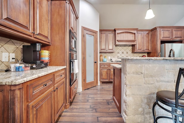 kitchen featuring light stone counters, stainless steel appliances, decorative light fixtures, and dark wood-type flooring