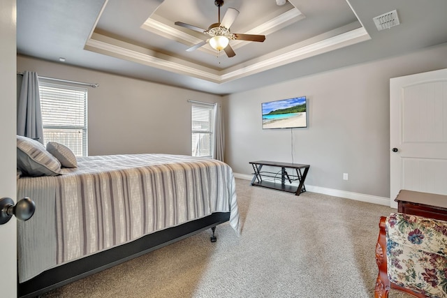 carpeted bedroom with ceiling fan, ornamental molding, and a tray ceiling