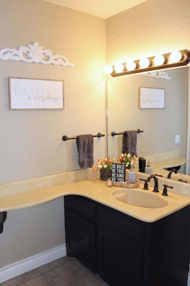 bathroom featuring tile patterned floors, a textured wall, and vanity