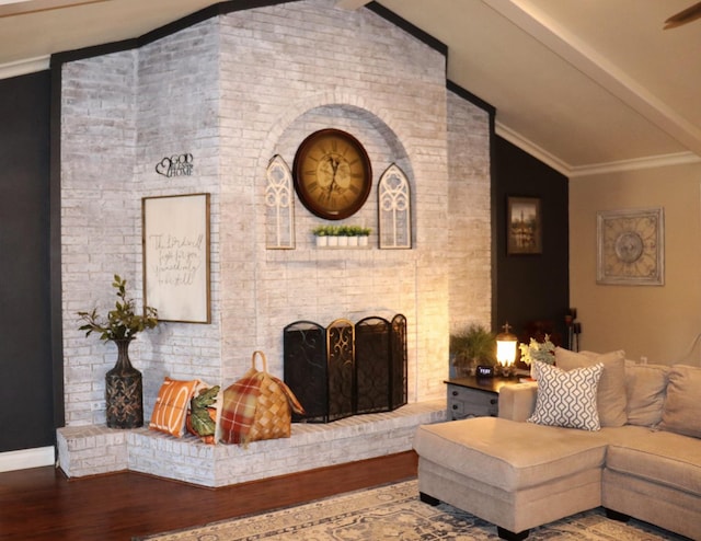 living room with baseboards, lofted ceiling, ornamental molding, wood finished floors, and a fireplace