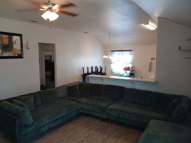 living room with vaulted ceiling, wood-type flooring, and ceiling fan with notable chandelier