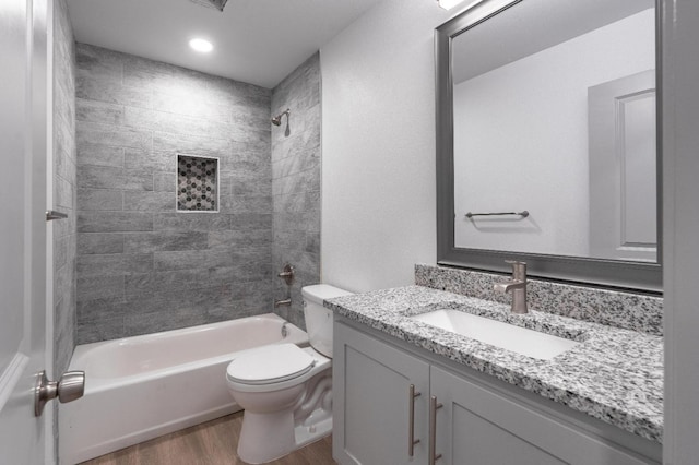 full bathroom featuring vanity, hardwood / wood-style floors, toilet, and tiled shower / bath