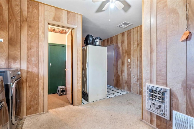 interior space with heating unit, washer and dryer, ceiling fan, and wood walls