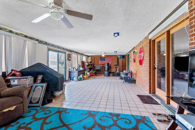 living room with tile patterned flooring, ceiling fan, brick wall, and a textured ceiling