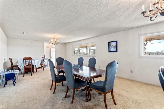 carpeted dining room with a textured ceiling and a chandelier