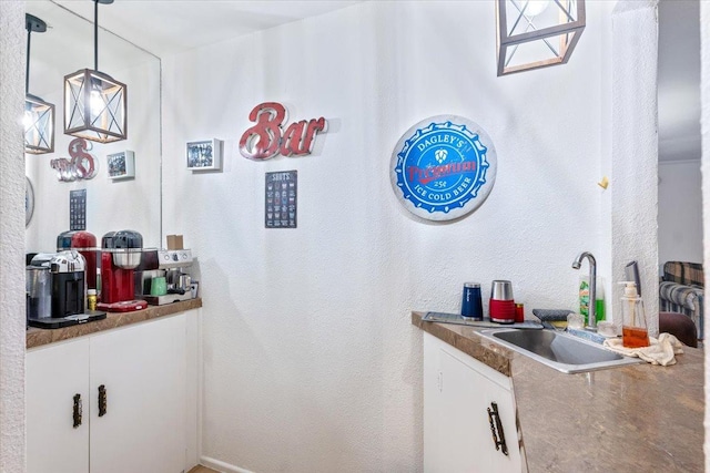 bar with pendant lighting, sink, and white cabinetry