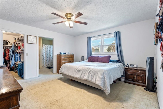 bedroom with light colored carpet, a spacious closet, a closet, and a textured ceiling