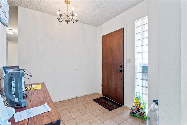 tiled entryway featuring a chandelier and a textured ceiling