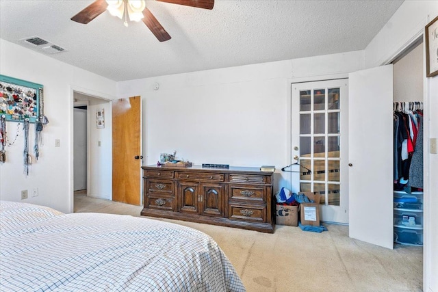 bedroom with ceiling fan, light colored carpet, a closet, and a textured ceiling