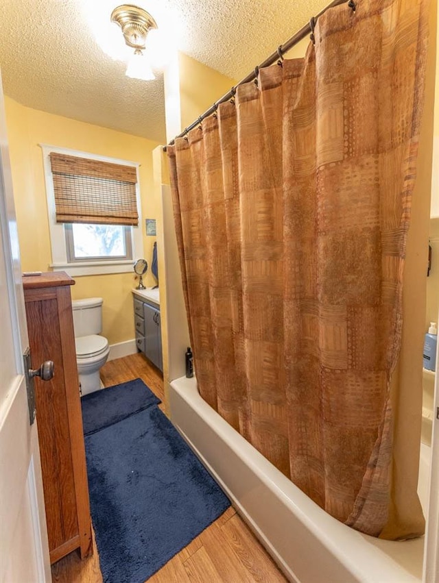 full bathroom featuring hardwood / wood-style floors, vanity, shower / tub combo, toilet, and a textured ceiling