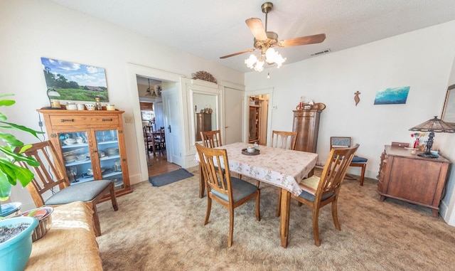 dining area featuring a textured ceiling, light colored carpet, and ceiling fan