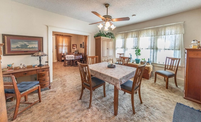 carpeted dining room featuring ceiling fan and a textured ceiling