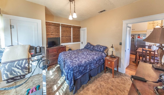 bedroom featuring stainless steel refrigerator and a textured ceiling