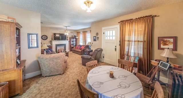 carpeted dining space featuring ceiling fan, a tiled fireplace, and a textured ceiling