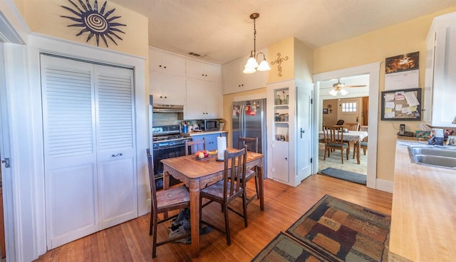 dining room featuring sink, a chandelier, and light hardwood / wood-style floors