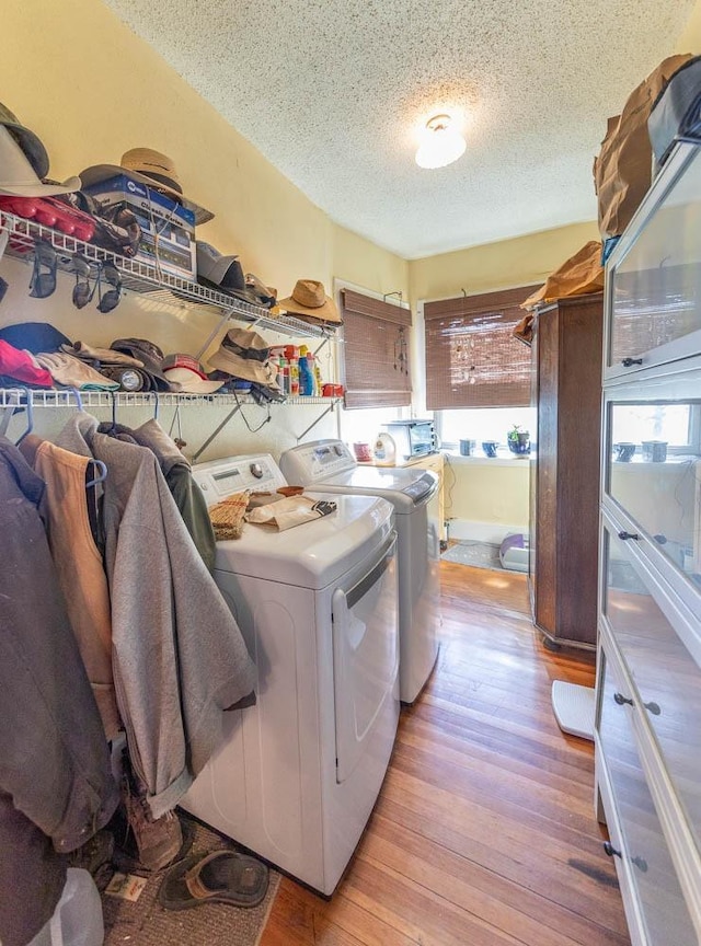 washroom featuring light hardwood / wood-style floors, independent washer and dryer, and a textured ceiling