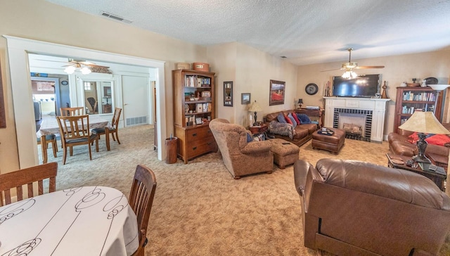 carpeted living room with ceiling fan, a fireplace, and a textured ceiling