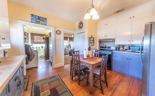 dining area with a chandelier, wood-type flooring, and washer / dryer