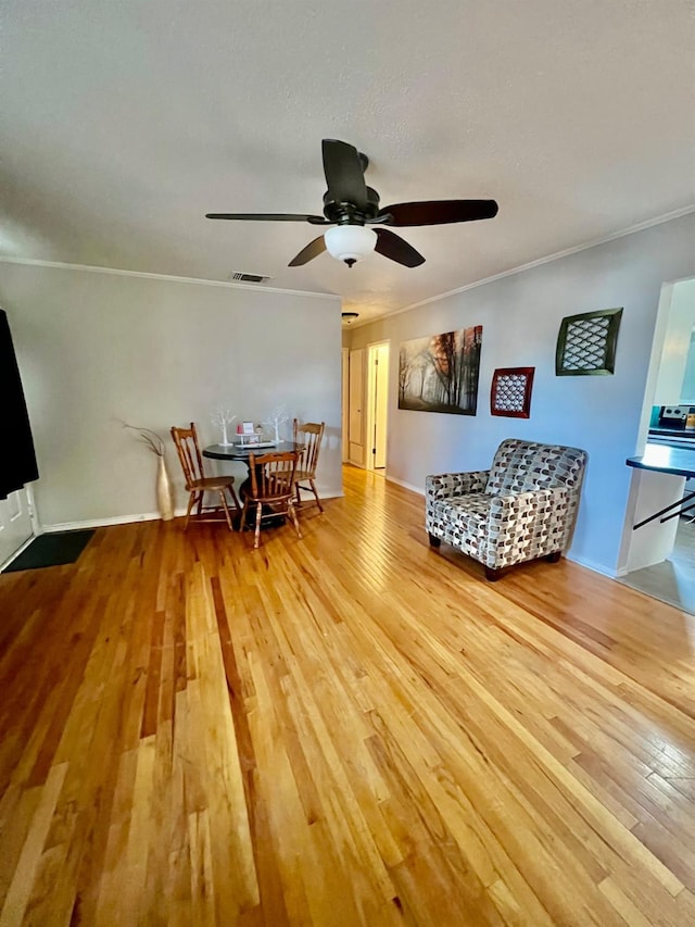 living room featuring hardwood / wood-style flooring, ornamental molding, and ceiling fan