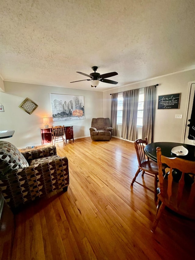living room with hardwood / wood-style flooring, ceiling fan, and a textured ceiling
