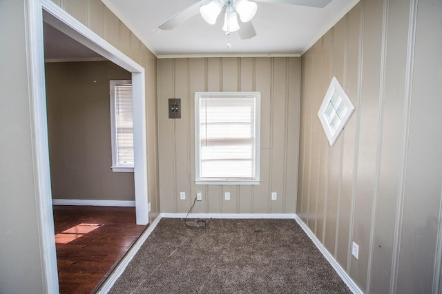 interior space featuring dark colored carpet, ornamental molding, and ceiling fan