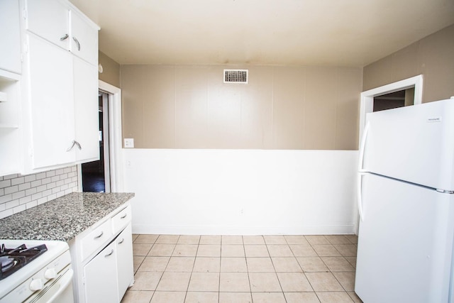 kitchen featuring stone counters, white fridge, white cabinets, and decorative backsplash