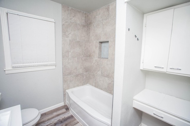 bathroom with tiled shower / bath, hardwood / wood-style floors, and toilet