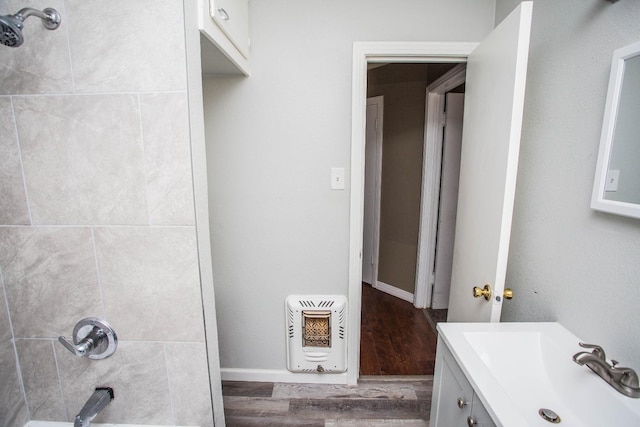 bathroom featuring tiled shower / bath combo, vanity, wood-type flooring, and heating unit