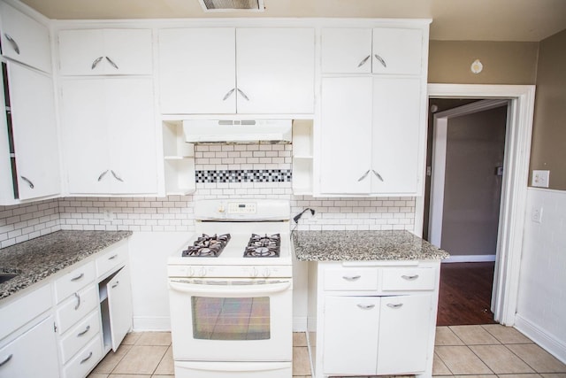 kitchen featuring light tile patterned floors, white gas range oven, white cabinetry, a center island, and light stone counters