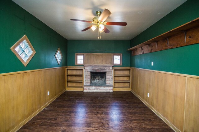 unfurnished living room featuring dark wood-type flooring, wooden walls, and ceiling fan