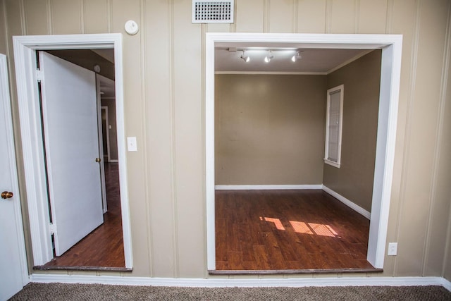 hallway with ornamental molding, wood-type flooring, and track lighting