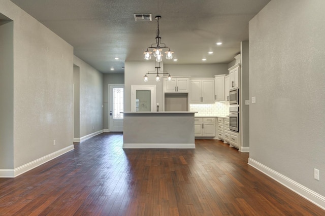 kitchen featuring dark hardwood / wood-style floors, white cabinets, pendant lighting, stainless steel appliances, and backsplash