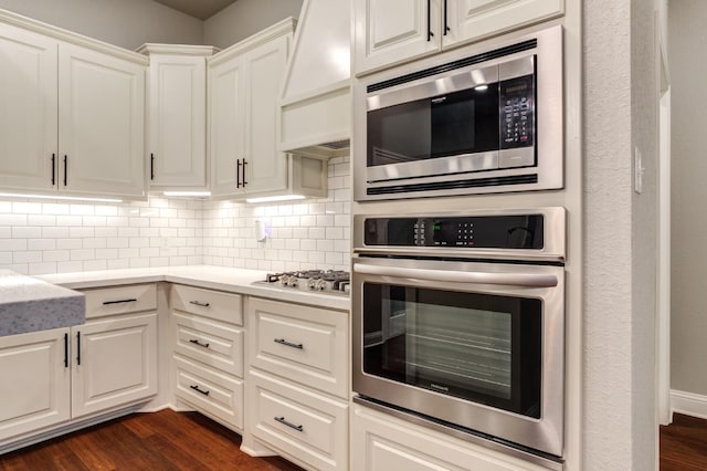 kitchen with stainless steel appliances, custom exhaust hood, dark hardwood / wood-style floors, and backsplash