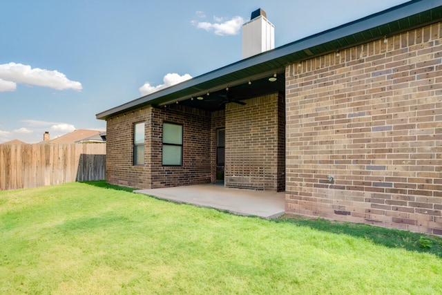 rear view of house with ceiling fan, a yard, and a patio area