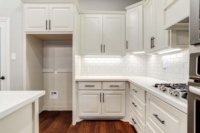 kitchen with dark hardwood / wood-style flooring, appliances with stainless steel finishes, white cabinets, and backsplash