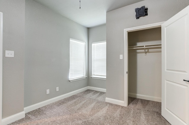 unfurnished bedroom with light colored carpet and a closet